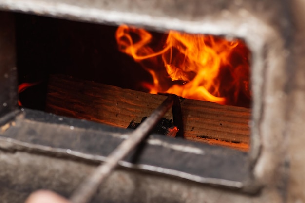 Rühren des Holzes mit Schürhaken im Heizkessel Festbrennstoff erneuerbare Energiequelle brennende Flammen