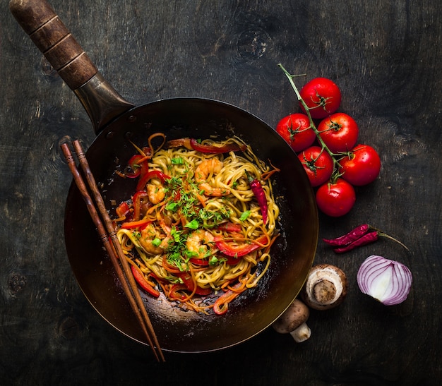 Rühren Sie braten Nudeln in traditionellen chinesischen Wok, Stäbchen. Asiatische Nudeln mit Gemüse, Garnelen.