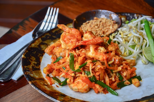 Rühren Sie Reisnudeln mit Garnelen und Gemüse oder Pad Thai auf Holztischhintergrund an