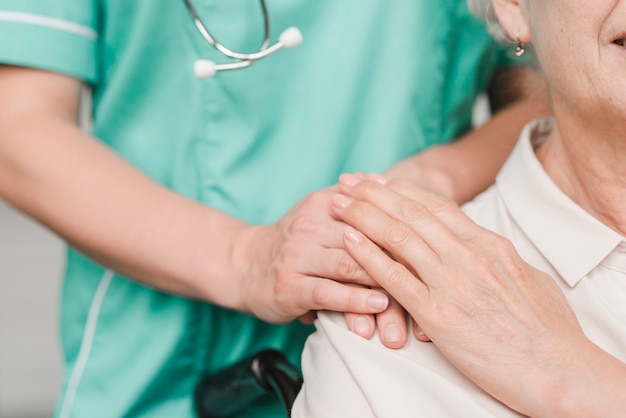 Foto rührende weibliche krankenschwesterhand der älteren frauenpatient auf schulter