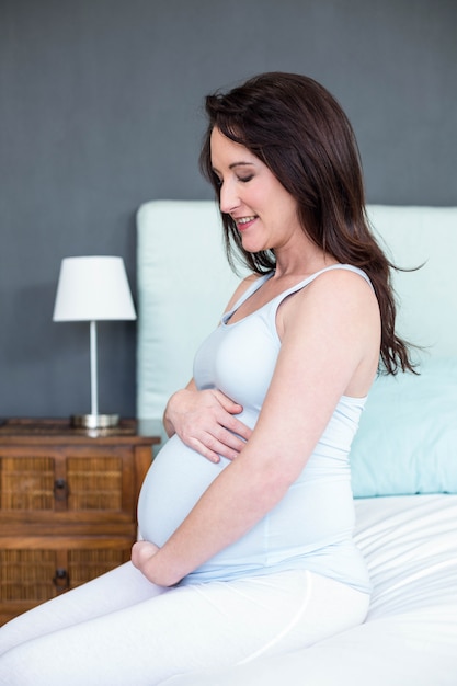 Rührender Bauch der schwangeren Frau in ihrem Schlafzimmer