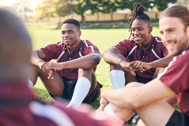 Rugby deportivo y hombres en el césped para descansar en la práctica de entrenamiento y ejercicio para el partido Trabajo en equipo de fitness y los hombres se relajan para planificar la estrategia para el desafío de competencia o el juego en el campo