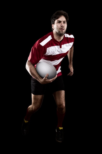 Rugby-Spieler in einer roten Uniform läuft. Schwarze Wand