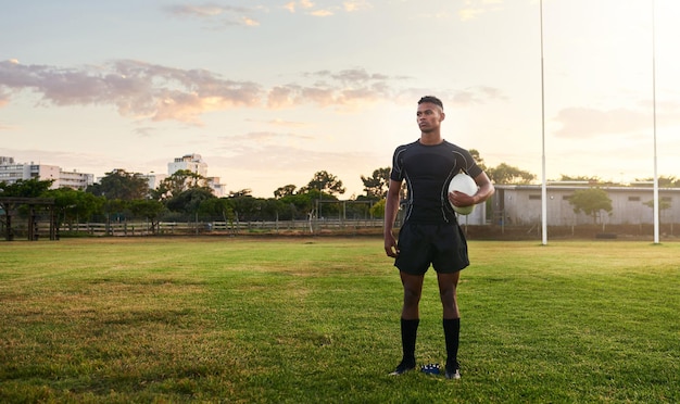 Rugbyspieler Sport und Stehen auf dem Feld mit Ball bereit für Spiel oder Training im Freien Sportlicher Sportler oder Profi wartet auf Rugby-Wettkampftraining oder Spielzeit auf grünem Gras