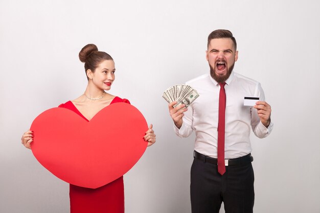 Foto rugido de hombre enojado, paga por amor, mujer sonriendo. interior, tiro del estudio, aislado en fondo gris