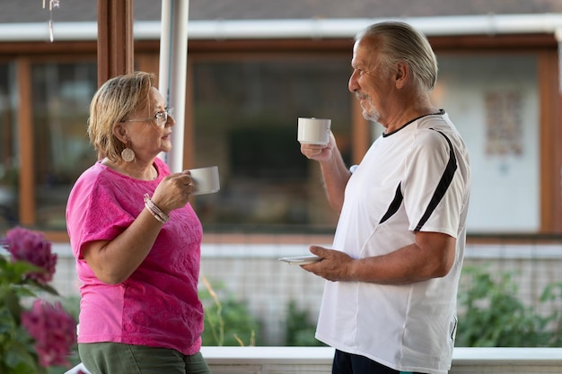 Foto ruhestand älteres ehepaar trinkt kaffee auf der veranda zwei ältere männer und frauen trinken kaffee und lächeln oder diskutieren zukunftspläne nach dem ruhestand