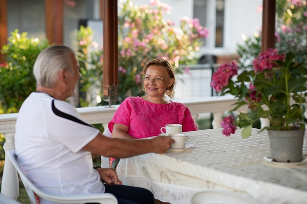 Ruhestand Älteres Ehepaar trinkt Kaffee auf der Veranda Zwei ältere Männer und Frauen trinken Kaffee und lächeln oder diskutieren Zukunftspläne nach dem Ruhestand