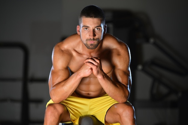 Ruhezeit Selbstbewusster, muskulöser junger Mann, der sich nach dem Training in einem gesunden Club-Fitnessstudio ausruht
