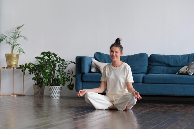 Foto ruhige brünette macht yoga im bett zu hause auf dem boden