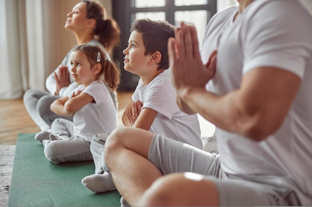 Ruhige familie, die zu hause zusammen yoga macht