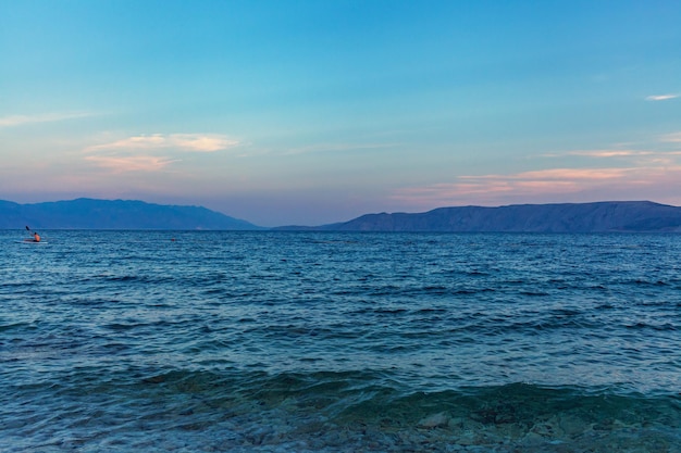 Ruhige Meereslandschaft, blaues Meer unter klarem Himmel, Berge am Horizont, Meereswellen, positiver Bildschirmschoner