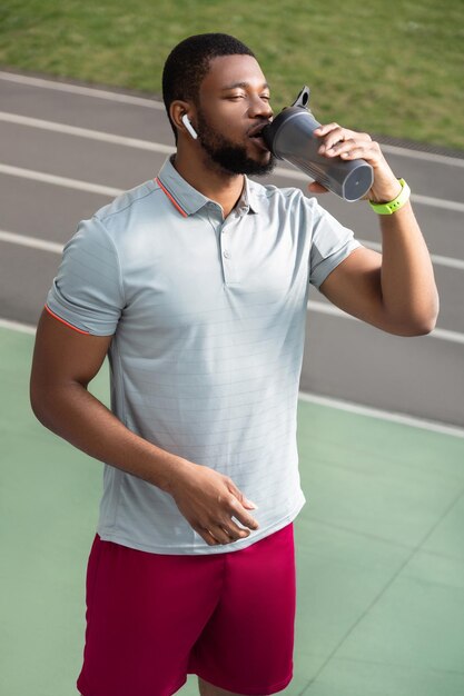 Ruhiger bärtiger junger Sportler in einem grauen T-Shirt