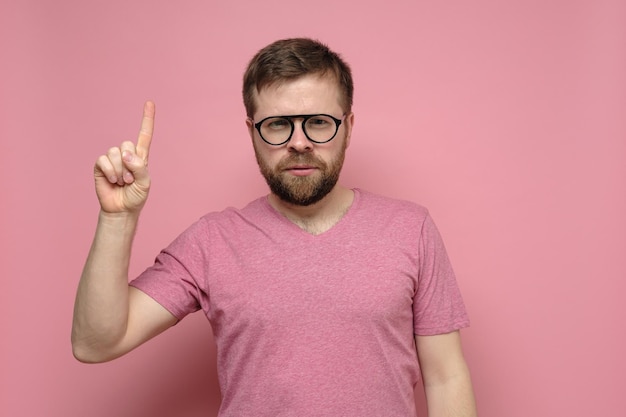 Ruhiger bärtiger Mann mit Brille zeigt mit dem Zeigefinger nach oben