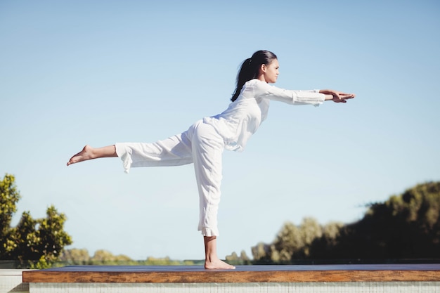 Ruhiger Brunette, der Yoga durch den Pool tut