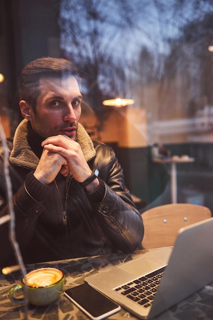 Ruhiger junger Mann im Café mit Gadgets