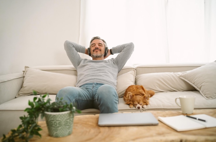 Foto ruhiger kaukasischer mann mittleren alters, der auf dem sofa sitzt und musik hört und meditation genießt