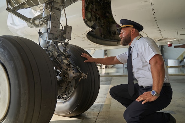 Ruhiger konzentrierter Pilot hockt vor dem Fahrwerk und legt eine Hand am Steuer