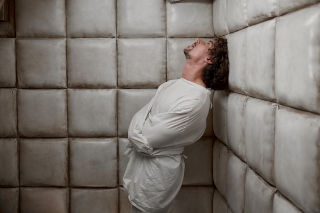Ruhiger Mann mit schizophrener psychischer Störung in einem weiß gepolsterten Zimmer