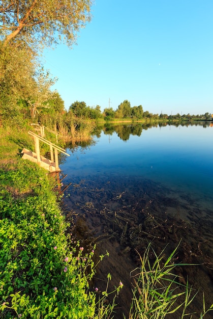 Ruhiger Strand des Sommersees mit Holzstegen zum Wasser