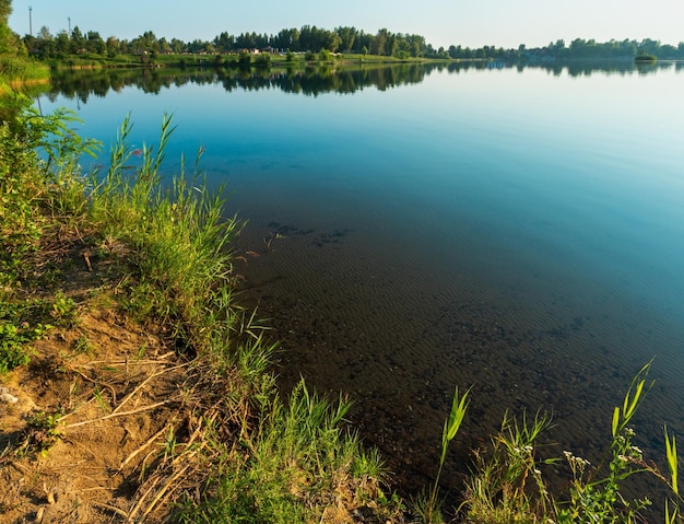 Ruhiger Strand des Sommersonnenuntergangsees