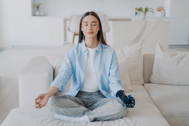 Ruhiges behindertes Mädchen macht Yoga mit bionischem Prothesenarm zu Hause Gesunder Lebensstil und Behinderung