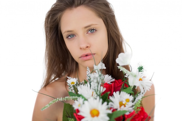 Ruhiges Brunettemodell, das einen Blumenstrauß von Blumen hält