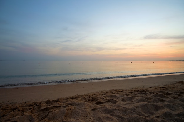 Ruhiges Meer mit Wellen am Sandstrand bei Sonnenaufgang.