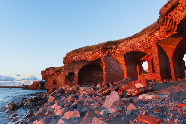 Las ruinas de la antigua fortaleza de ladrillo brillaron con rayos solares en la orilla del paisaje del mar Báltico