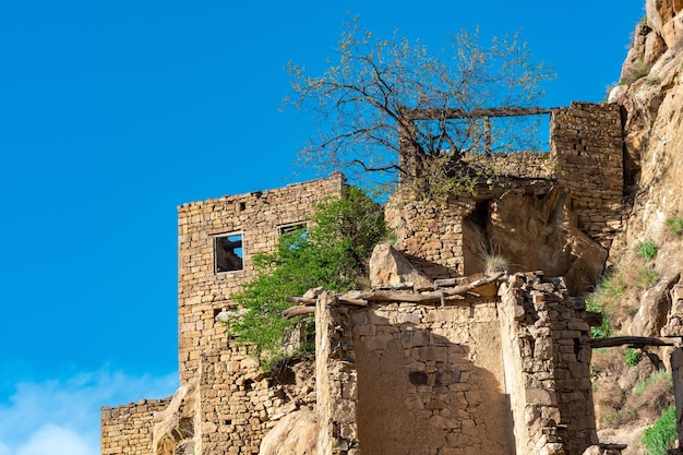 Ruinas de casas de piedra unidas a la roca en el pueblo despoblado de Gamsutl en Daguestán