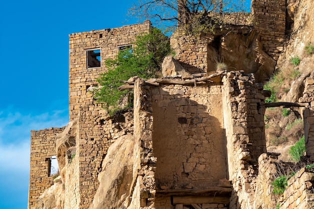 Ruinas de casas de piedra unidas a la roca en el pueblo despoblado de Gamsutl en Daguestán