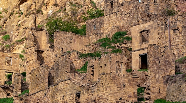 Foto ruinas de casas de piedra unidas a la roca en el pueblo despoblado de gamsutl en los rayos del atardecer