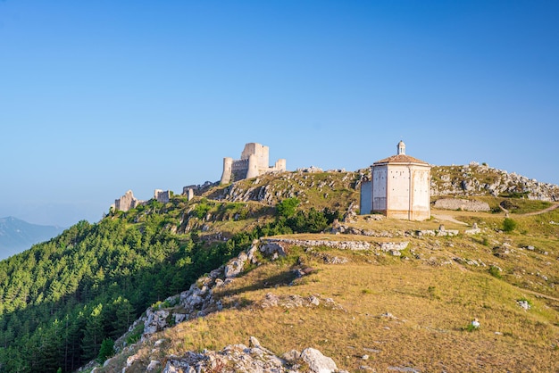 Ruínas do castelo e pequena capela no destino de viagem italiano rocca calascio, marco no parque nacional gran sasso, abruzzo, itália. céu azul claro
