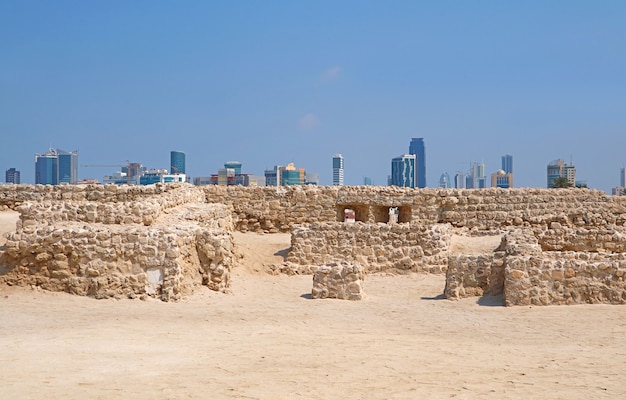 Ruínas do Forte do Bahrein ou Qal'at al-Bahrain com a paisagem urbana moderna de Manama no pano de fundo, Bahrein