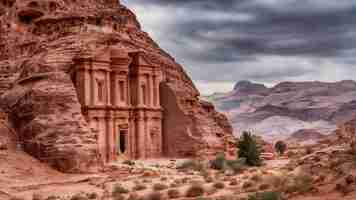 Foto ruinas del monasterio de ad deir talladas en la pared rocosa en petra jordania terreno montañoso con nubes