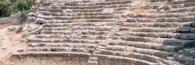 Ruinierter Bau des alten Amphitheatergebäudes Erkunden Sie die antiken Ausgrabungen der Ruinen der antiken lykischen Stadt Phaselis in der Türkei in der Sommernatur im Outdoor-Banner der Berge