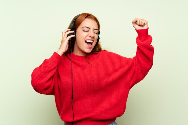 Ruiva adolescente com camisola, ouvindo música com fones de ouvido