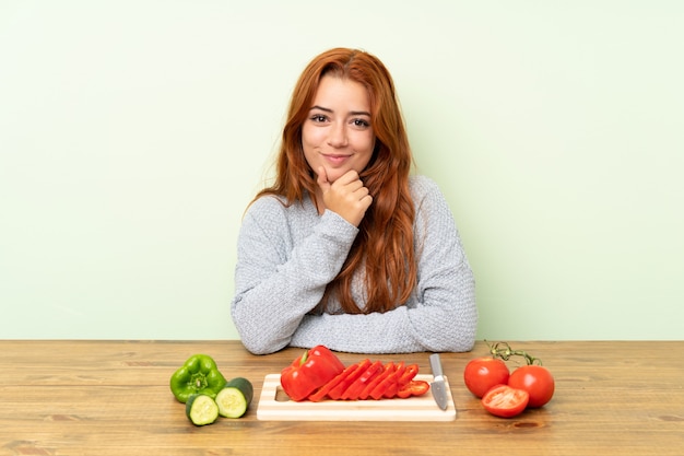 Ruiva adolescente com legumes em uma mesa rindo