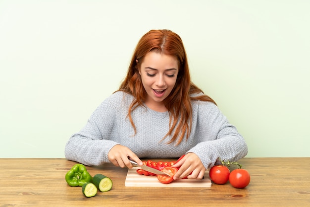 Ruiva adolescente com legumes em uma mesa