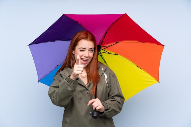 Ruiva adolescente mulher segurando um guarda-chuva aponta o dedo para você