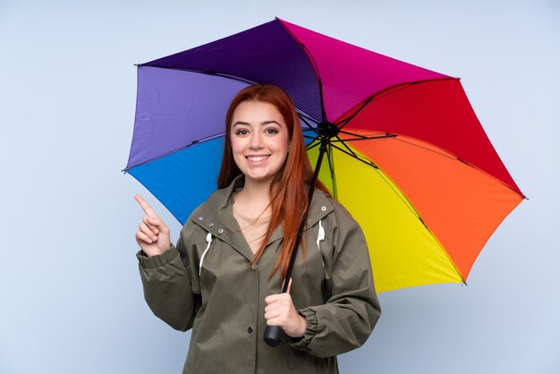 Ruiva adolescente mulher segurando um guarda-chuva, apontando o dedo para o lado