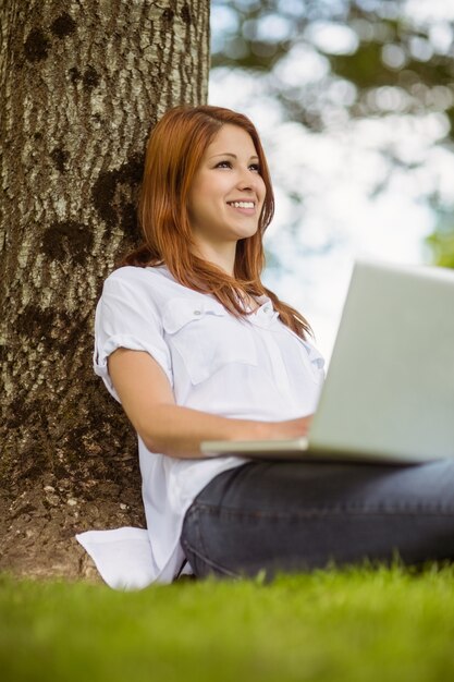 Ruiva bonita sorrindo com seu laptop