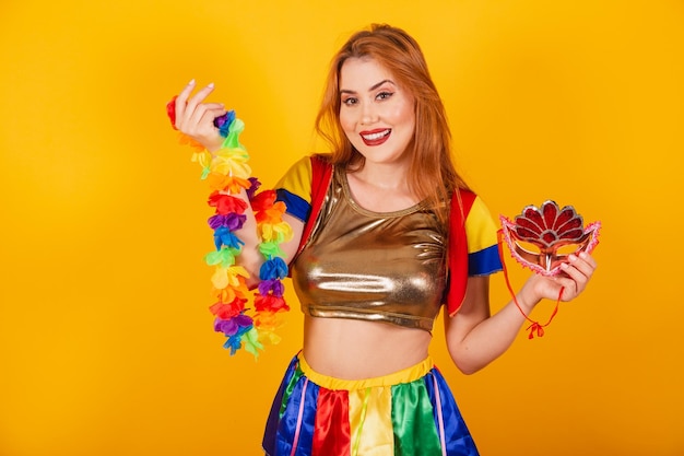 Ruiva brasileira com roupas de carnaval frevo e guarda-sol colorido segurando máscara e colar de flores