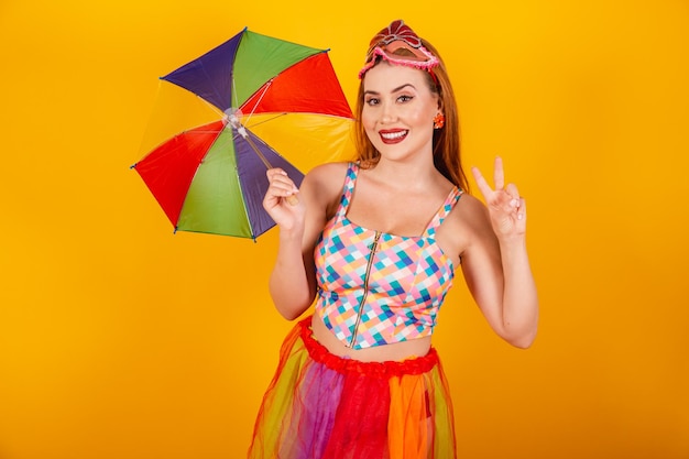 Ruiva brasileira em roupas de carnaval com um guarda-sol colorido paz e amor
