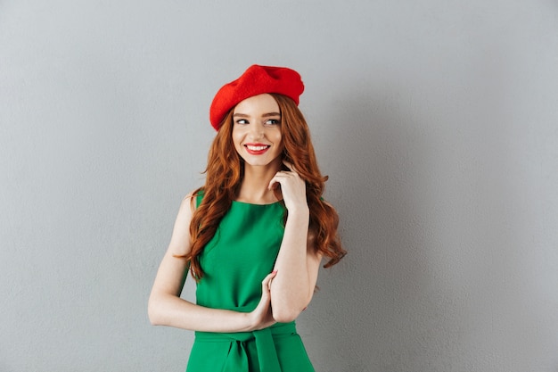 Ruiva feliz jovem em vestido verde e boina vermelha