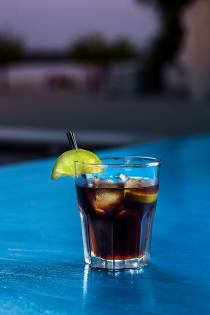 Rum-Cola-lässiger Cocktail mit Eiswürfeln und Limette am Sommerbarstandhintergrund