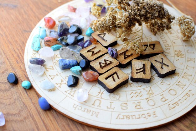 Runas escandinavas hechas de ametista y cristales de cuarzo rosa en un tablero con símbolos del zodiaco
