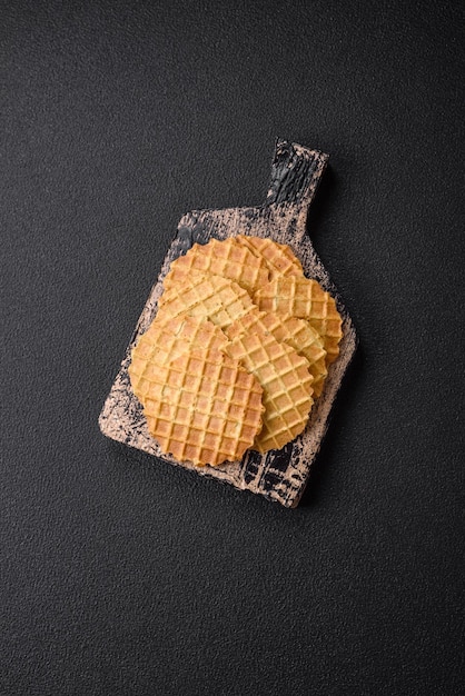 Runde, knusprige Waffeln für die Zubereitung süßer, köstlicher Desserts oder Snacks auf dunklem Betonhintergrund