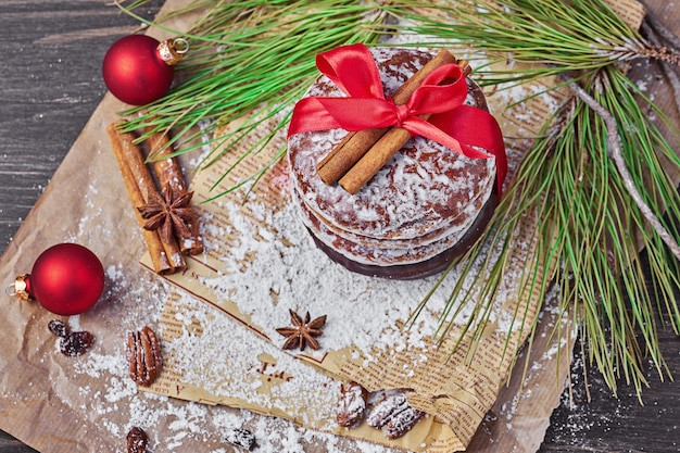 Runde Plätzchen des Weihnachtslebkuchens gebunden mit rotem Band, Zimtstangen, Sternanisen und Tannenzweigen