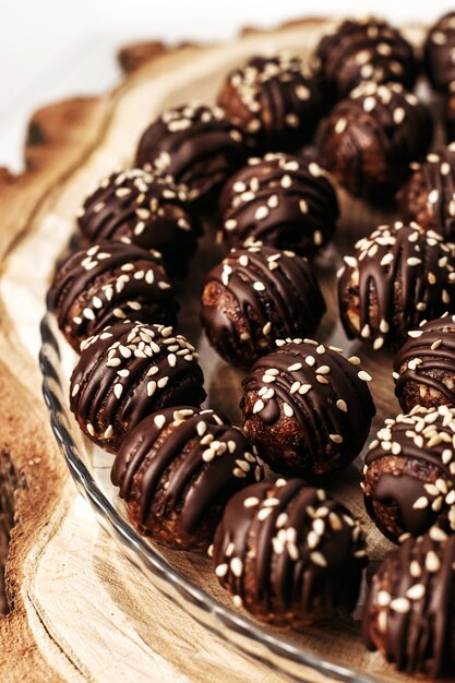 Runde Pralinenbonbons mit Sesam. Dunkler Hintergrund, Luxusdessert, dunkle Schokolade, handgemacht.