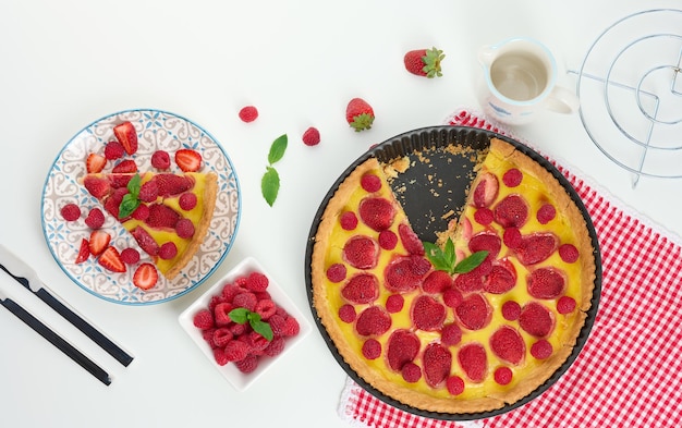 Runde Quiche mit roten Erdbeeren und Himbeeren auf einem weißen Tisch